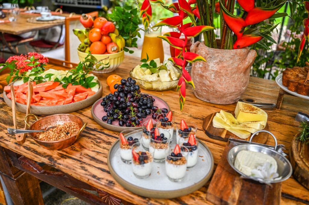 Buffet de café da manhã do Preta Bistrô, no MAC_Bahia, em Salvador, com preparações nordestinas, pães, frutas, frios e sobremesas.